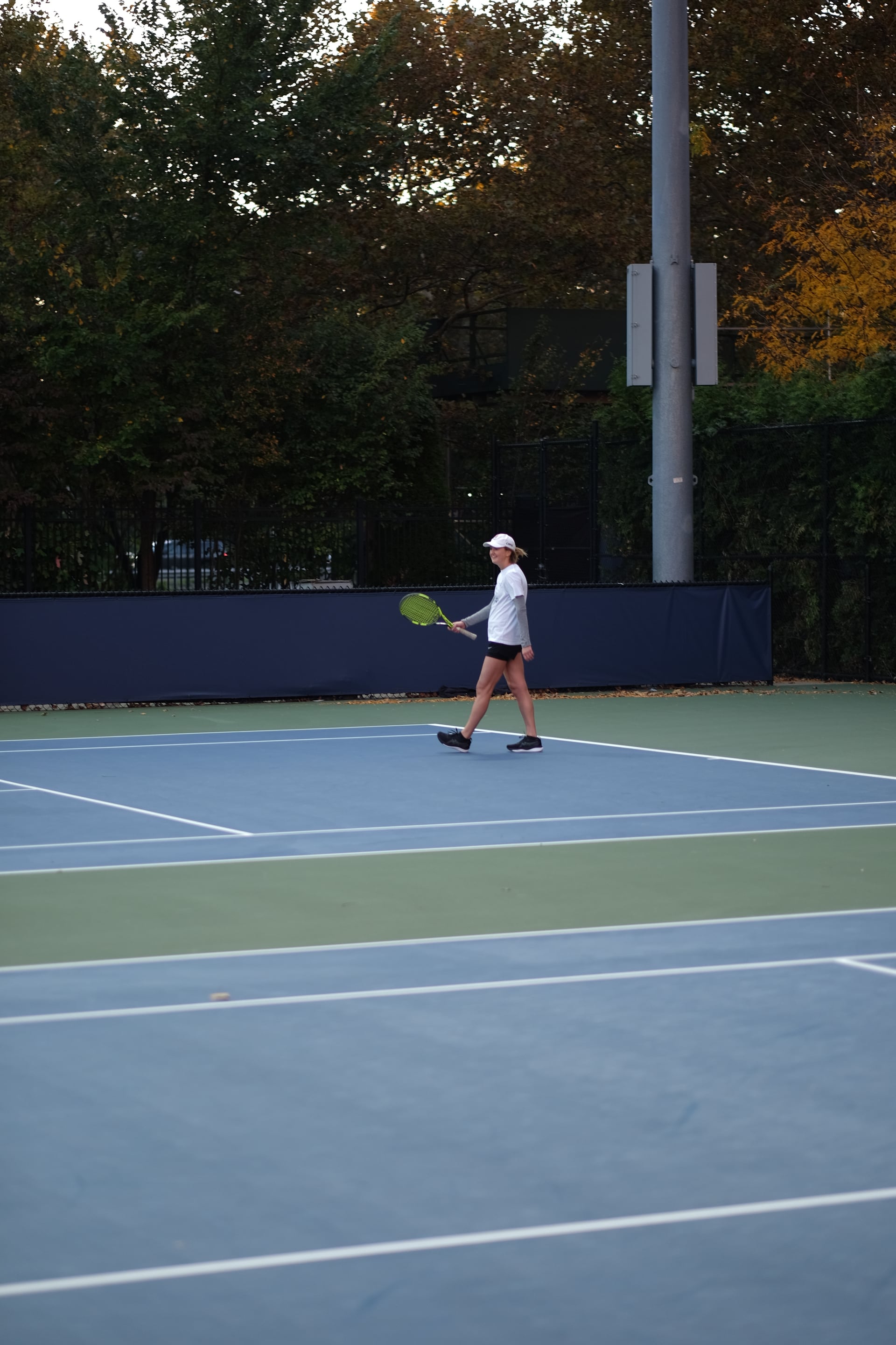 A player smiling between points beneath the autumn trees at Saturday Sunset Club, October 17, 2026