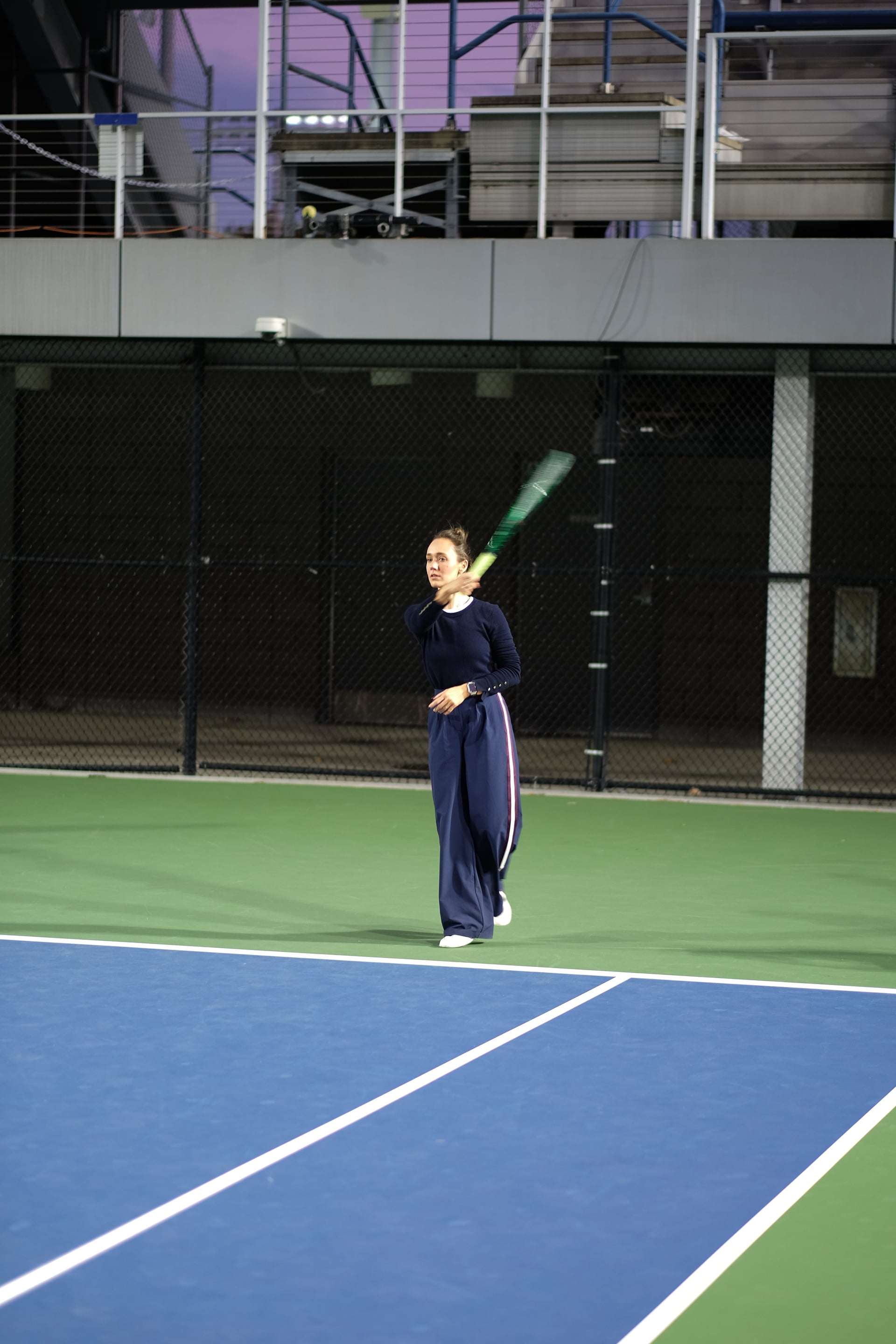 A player following through on a groundstroke under the court lights at Saturday Sunset Club, October 17, 2026