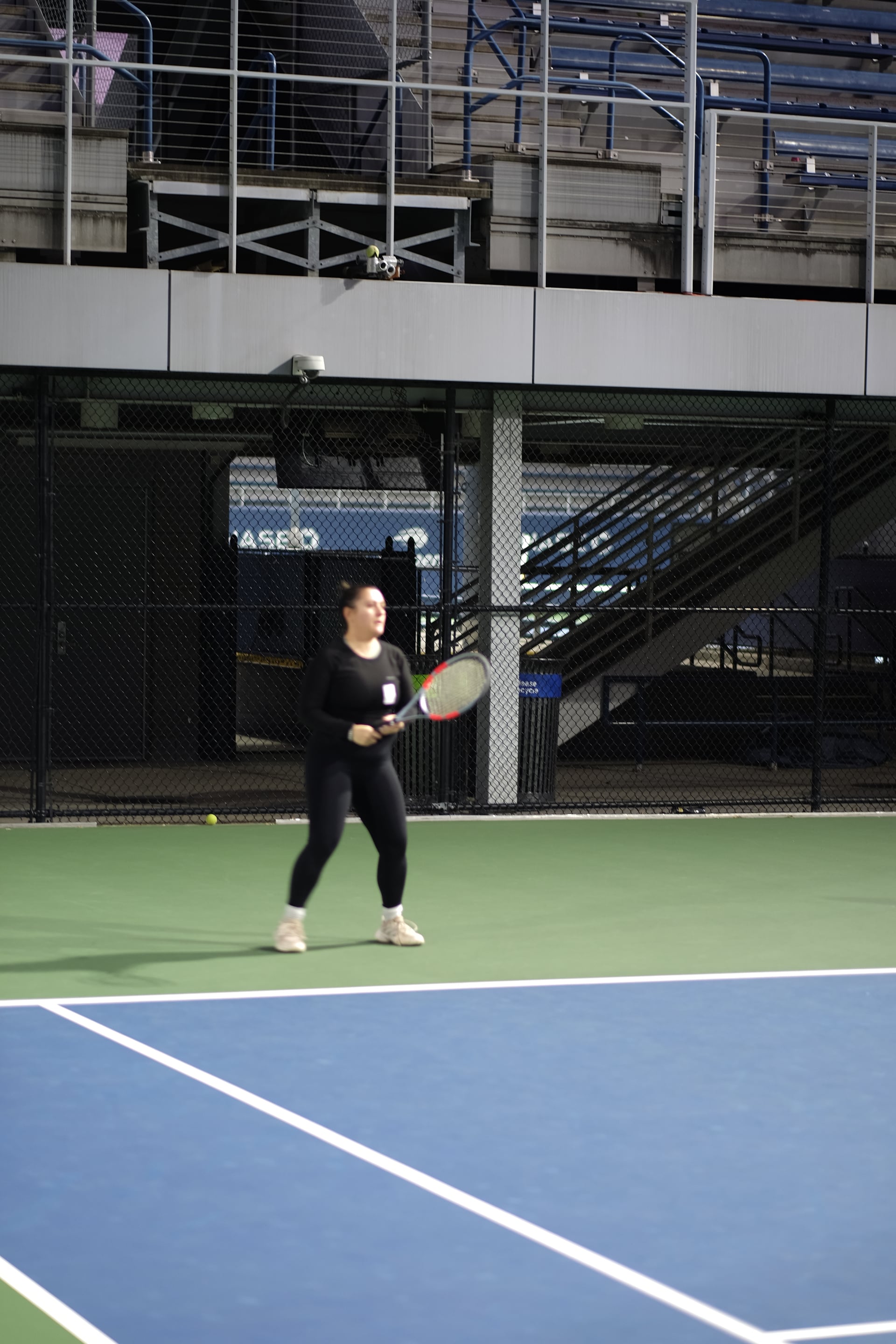 A player ready for a return beside the practice-court stands at Saturday Sunset Club, October 17, 2026