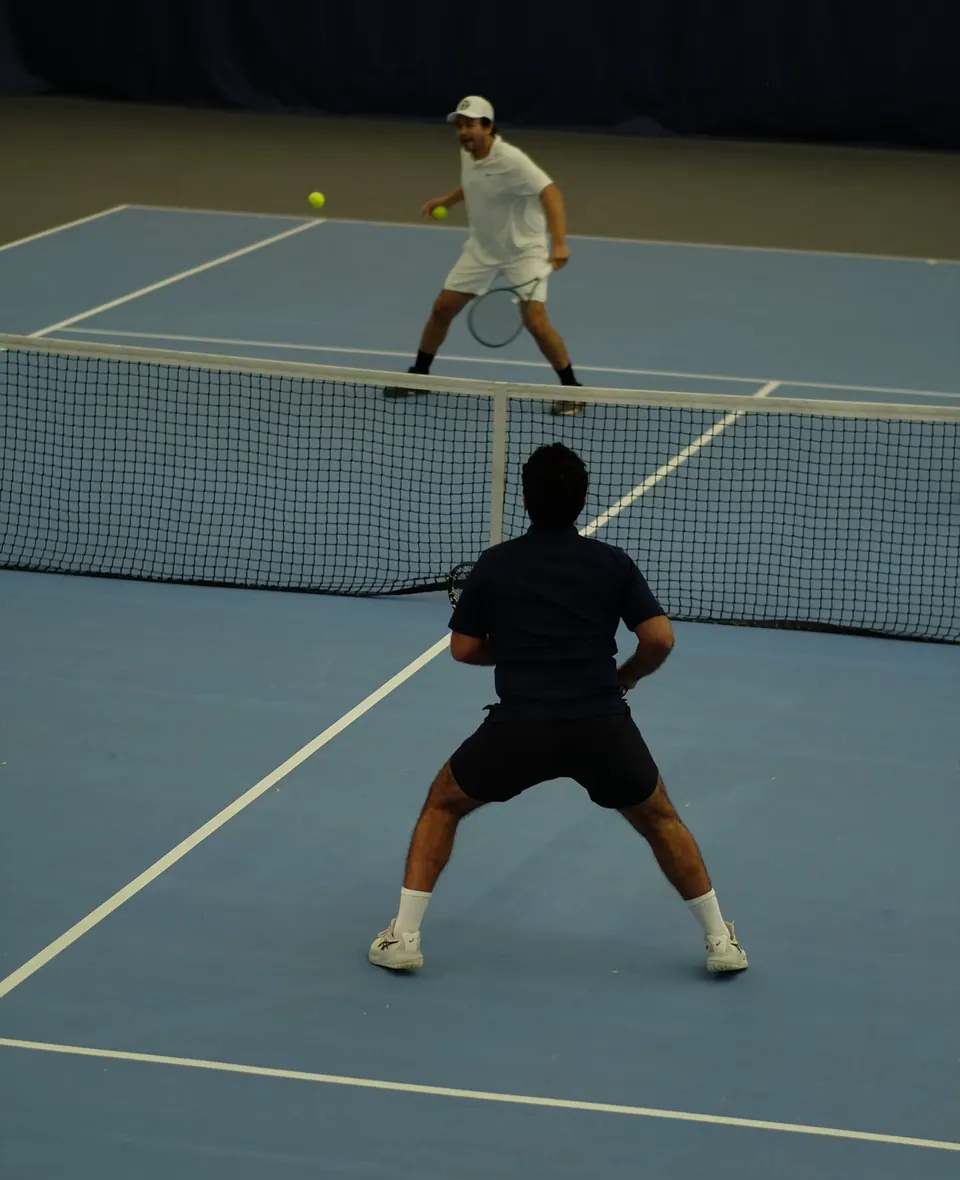 Tennis players playing doubles under the lights at an indoor New York tennis club